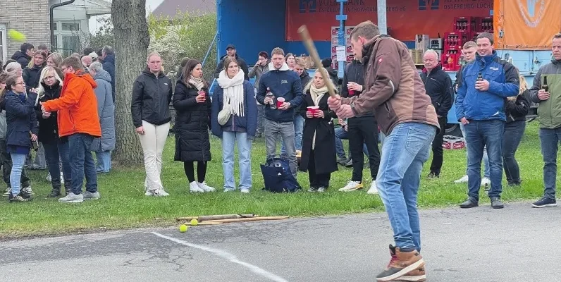 bild mit schlagball-spieler und zuschauenden am straßenrand