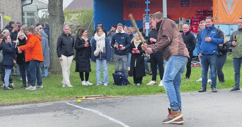 bild mit schlagball-spieler und zuschauenden am straßenrand